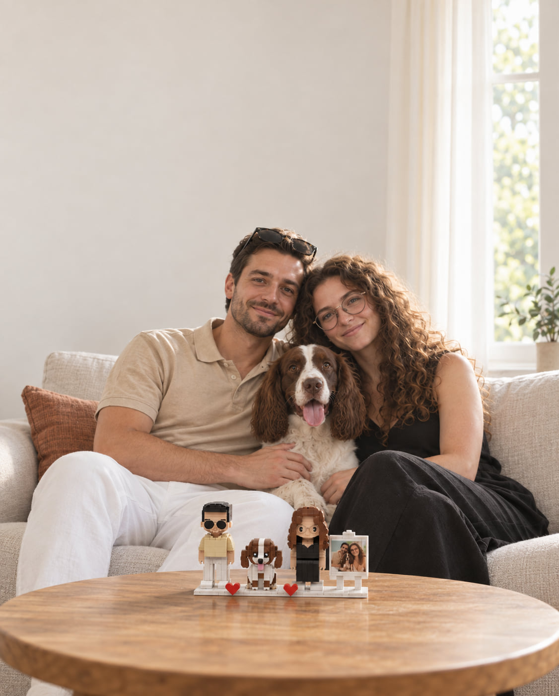 A couple and their spaniel on a sofa with their custom brick portrait kit of the three of them on the coffee table